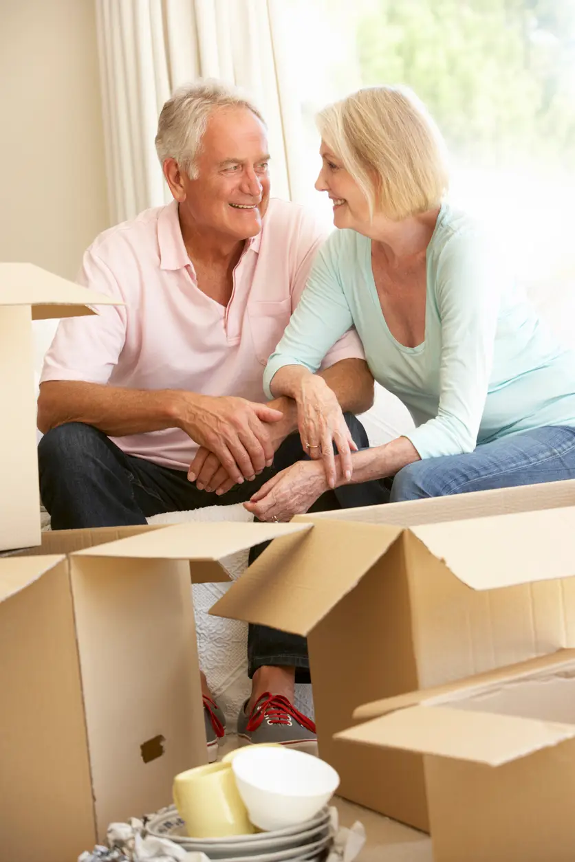 Senior Couple Moving Into New Home Surrounded By Packing Boxes