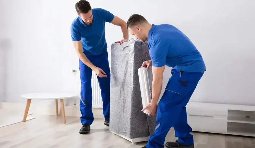 Two men wrapping a large furniture. Excellent moving services from a top local mover company.