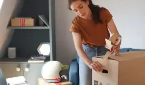 Girl from a small move company packing up cargo in boxes.